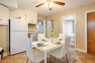 a kitchen and dining room with a white table and chairs at Appartement moderne 3 chambres avec spa, jardin privé & parking gratuit - accès autonome in Saint-Jean-sur-Richelieu