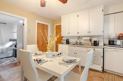 a white kitchen with a white table and chairs at Appartement moderne 3 chambres avec spa, jardin privé & parking gratuit - accès autonome in Saint-Jean-sur-Richelieu