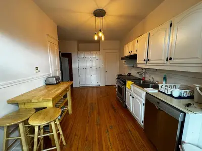 a kitchen with white cabinets and a wooden counter top at Beautiful Sunny big apartment in Montréal