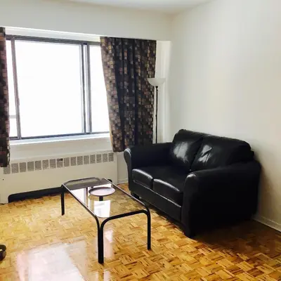 a living room with a black leather couch and a glass table at Stylish Montreal Apartment Comfortable Stay in the Golden Square Mile in Montréal