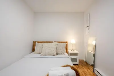 a white bedroom with a bed and a mirror at Charming 2BR in Plateau Mont-Royal in Montréal