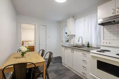 a kitchen with white cabinets and a table with chairs at Charming 2BR in Plateau Mont-Royal in Montréal
