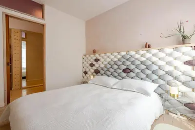 a bedroom with a large white bed with a padded headboard at Bel appartement confortable - Emplacement idéal in Montréal