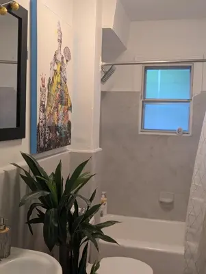 a bathroom with a painting on the wall and a plant at Espace Cozy - 2 bed in Longueuil