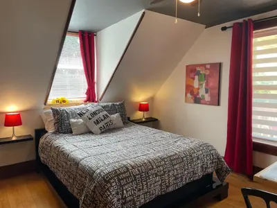 a bedroom with a bed and two windows with red curtains at Auberge La Table d'Hôte in West Brome