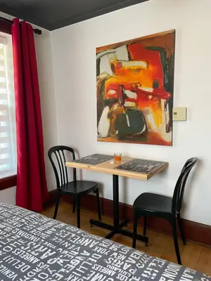 a table with two chairs and a painting on the wall at Auberge La Table d'Hôte in West Brome