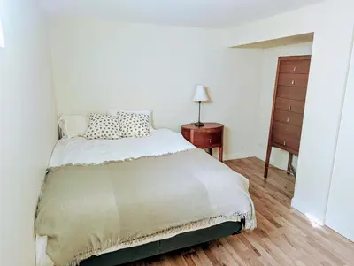 a white bedroom with a bed and a dresser at Fully furnished cozy home in Montréal