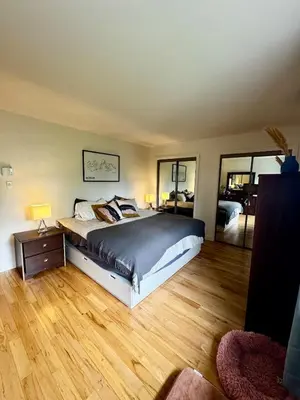 a bedroom with a large bed and wooden floors at Fully furnished cozy home in Montréal