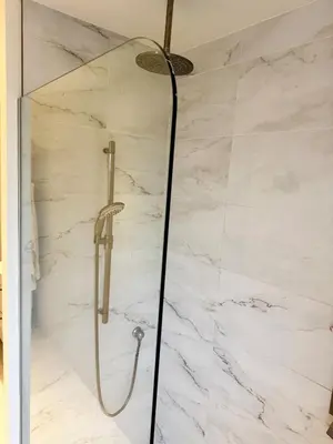 a shower in a bathroom with white marble walls at Fully furnished cozy home in Montréal