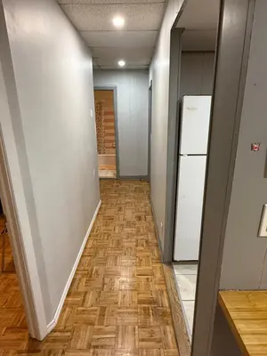 an empty hallway with a refrigerator and wooden floors at Montreal Accommodation Steps Downtown 17mins airport in Montréal