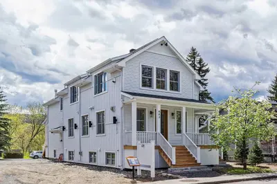 a white house with a porch and stairs at room with shared bathrooms 883 Shefford in Bromont
