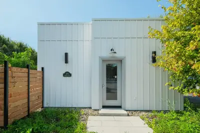 a white building with a door and a fence at room with shared bathrooms 883 Shefford in Bromont