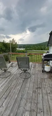a deck with two chairs and a grill and a piano at La détente in Disraeli