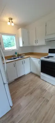 a kitchen with white cabinets and a sink and a stove at La détente in Disraeli