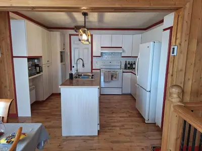 a kitchen with white cabinets and a white refrigerator at Le Repos Du Lac Aylmer in Disraeli