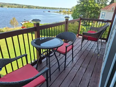 a deck with chairs and a table with a view of the water at Le Repos Du Lac Aylmer in Disraeli