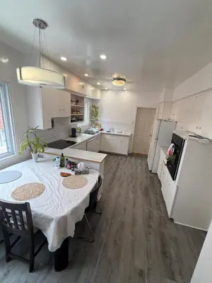 a white kitchen with a table and a refrigerator at Montréal Downtown Private Rooms Across Polytechnique in Montréal