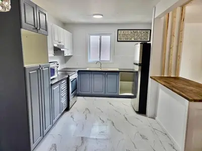 a kitchen with blue and white cabinets and a refrigerator at Escapade Marie-Isabelle in Montréal