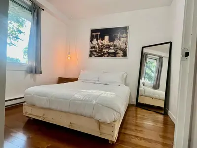 a white bedroom with a bed and a mirror at Escapade Marie-Isabelle in Montréal