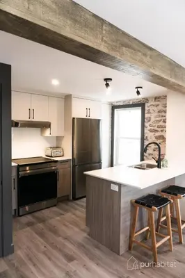 a kitchen with white cabinets and a counter top at Studio 21 charme et confort au coeur de Magog in Magog-Orford