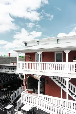 a red building with a white balcony and tables at Studio 21 charme et confort au coeur de Magog in Magog-Orford