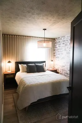 a bedroom with a large bed with two lamps on tables at Studio 21 charme et confort au coeur de Magog in Magog-Orford