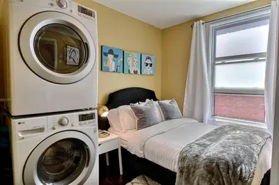 a bedroom with a bed and a washing machine at Sacha's Home Away in Quiet Montreal in Montréal