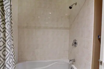 a bathroom with a white tub and a shower at Sacha's Home Away in Quiet Montreal in Montréal