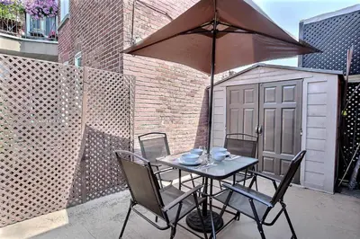 a table with chairs and an umbrella on a patio at Ground Floor Loft Style Luxury Executive Flat in Montréal