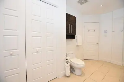 a white bathroom with a toilet and two white doors at Ground Floor Loft Style Luxury Executive Flat in Montréal