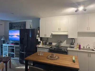 a kitchen with white cabinets and a black refrigerator at la voyageuse in Longueuil