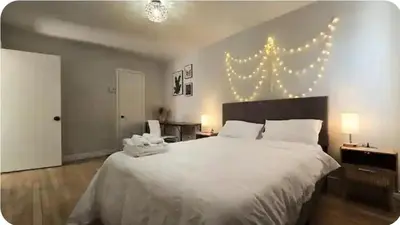a bedroom with a large white bed with lights on the wall at Boho style Private rooms in a shared three rooms apartment in Montréal