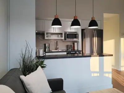 a kitchen with stainless steel appliances and a couch at Chalet Tranquillité Orford in Magog-Orford