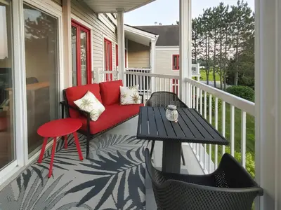 a porch with a red couch and a table at Chalet Tranquillité Orford in Magog-Orford