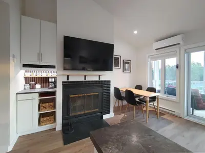 a living room with a fireplace and a table with chairs at Chalet Tranquillité Orford in Magog-Orford