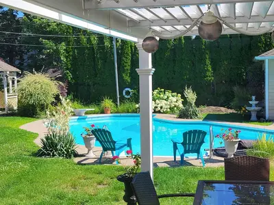 a pergola with chairs and a swimming pool at Chez Carole - Établissement d'hébergement de résidence principale sur la Rive-Sud de Montréal in Mercier