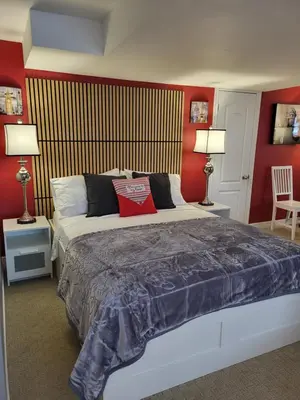 a bedroom with a bed with red walls and two lamps at Chez Carole - Établissement d'hébergement de résidence principale sur la Rive-Sud de Montréal in Mercier
