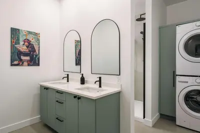 a bathroom with a sink and a washing machine at Chalet a Samia - Spa, luxury, Jay Peak view in Mansonville