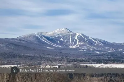 a snow covered mountain in the middle of a field at Chalet a Samia - Spa, luxury, Jay Peak view in Mansonville