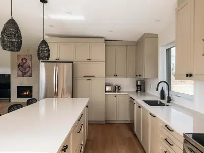 a kitchen with white cabinets and a refrigerator at Chalet a Samia - Spa, luxury, Jay Peak view in Mansonville