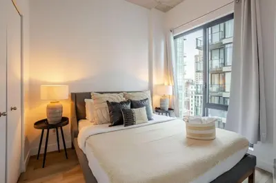 a bedroom with a bed and a large window at Elegant 1BR Retreat and Chic Stay in Old Port in Montréal