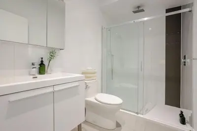 a white bathroom with a toilet and a glass shower at Elegant 1BR Retreat and Chic Stay in Old Port in Montréal