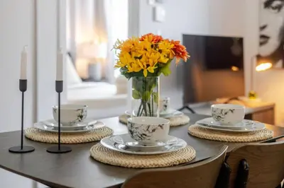 a table with cups and a vase of flowers on it at Elegant 1BR Retreat and Chic Stay in Old Port in Montréal