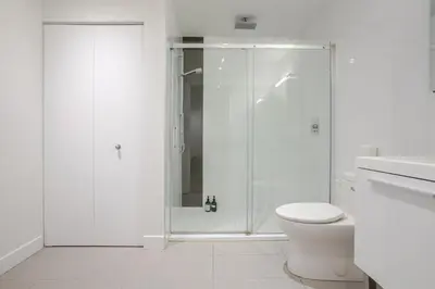 a white bathroom with a shower and a toilet at Roomy 1BR Getaway MTL Old Port in Montréal