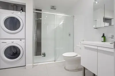 a white bathroom with a washing machine and a toilet at Roomy 1BR Getaway MTL Old Port in Montréal