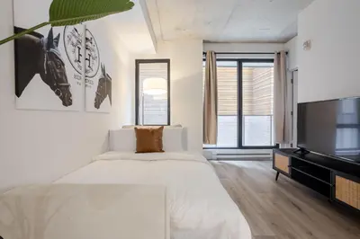 a white bedroom with a large bed and a flat screen tv at Roomy 1BR Getaway MTL Old Port in Montréal