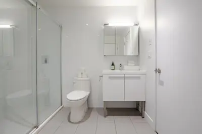 a white bathroom with a toilet and a shower at Roomy 1BR Getaway MTL Old Port in Montréal
