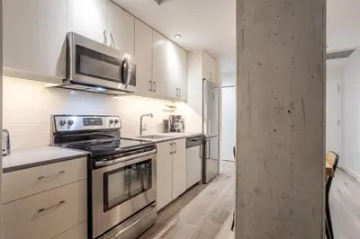 a kitchen with stainless steel appliances and white cabinets at Roomy 1BR Getaway MTL Old Port in Montréal