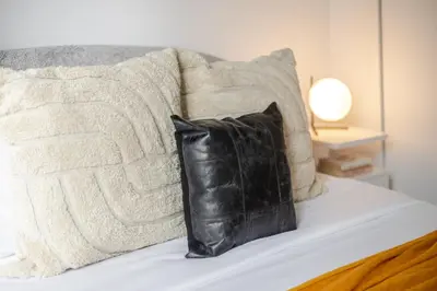a black leather pillow sitting on a bed with pillows at Sophisticated 1BR Escape , Charm in Old Port in Montréal