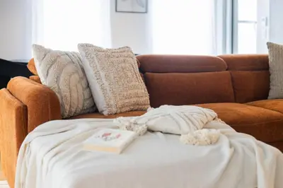 a blanket on a couch with a book on it at Exclusive Sanctuary Elegance Meets Comfort in Montréal